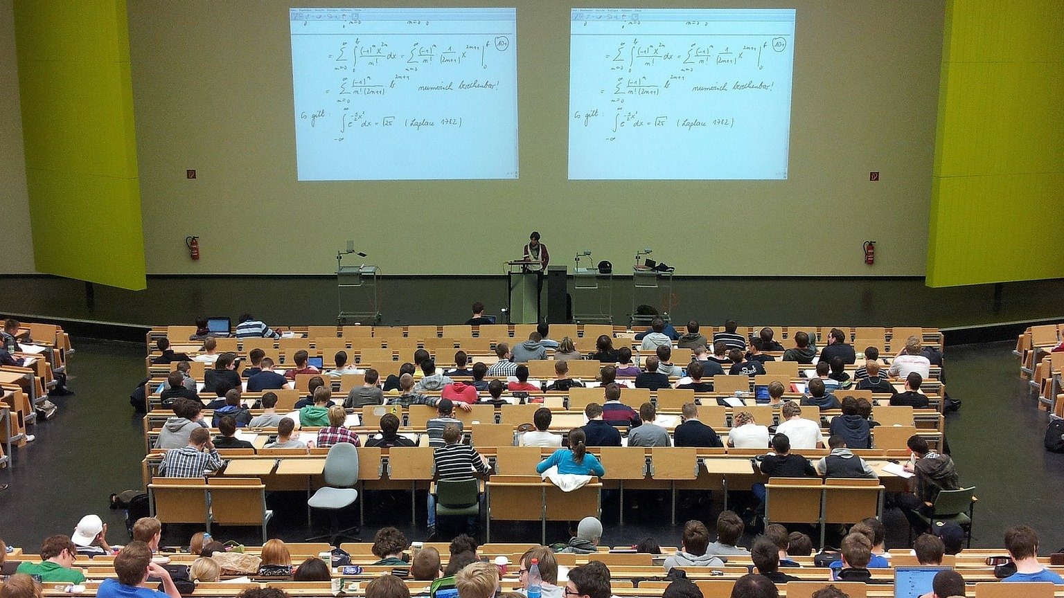 Vorlesungssaal mit Menschen vor einer Leinwand